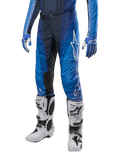 Alpinestars Techstar Pneuma Pants 2024, spodnie motocrossowe, ciemnogranatowy i jasnoniebieski, noszone z pasującą niebieską bluzą i białymi butami, białe logo na udzie, teksturowane strefy przyczepności, smukły sportowy design do wyścigów terenowych