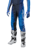 Alpinestars Techstar Pneuma Pants 2024, spodnie motocrossowe, ciemnogranatowy i jasnoniebieski, noszone z pasującą niebieską bluzą i białymi butami, białe logo na udzie, teksturowane strefy przyczepności, smukły sportowy design do wyścigów terenowych