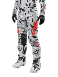 Spodnie Alpinestars Techstar Rantera 2024, spodnie motocrossowe, wzór Haze Gray Camo z czarnym i czerwonym abstrakcyjnym motywem, zestawione z pasującą koszulką, czarnymi rękawicami i białymi butami motocrossowymi, zaprojektowane do wyczynowej jazdy off-road