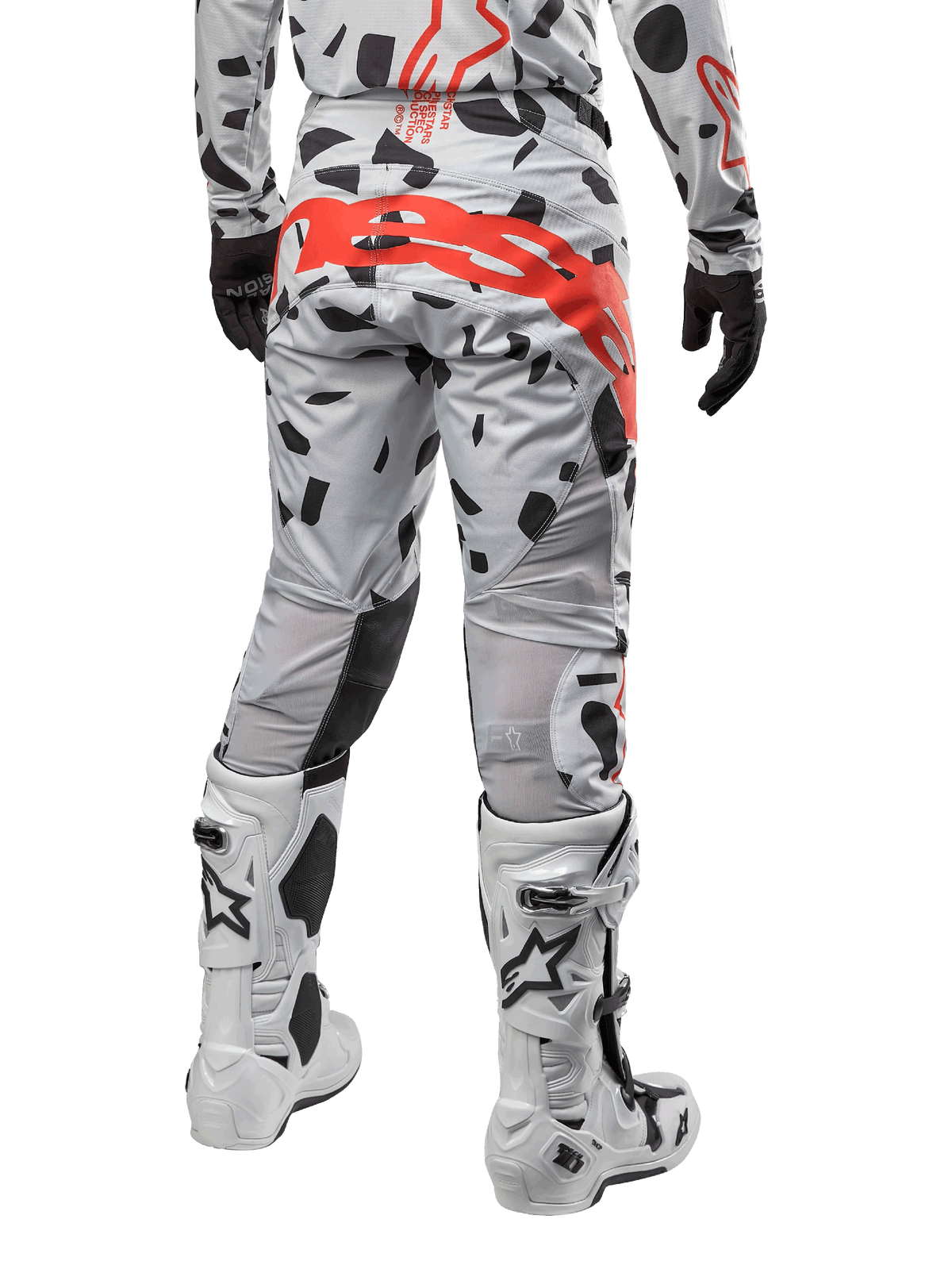 Alpinestars Techstar Rantera Pants 2024, spodnie motocrossowe, kolor Haze Gray Camo, czarne wzory kamuflażu i duże czerwone logo Alpinestars na siedzeniu, widok z tyłu w białych butach i pasującej odzieży wyścigowej