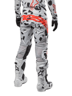 Alpinestars Techstar Rantera Pants 2024, spodnie motocrossowe, kolor Haze Gray Camo, czarne wzory kamuflażu i duże czerwone logo Alpinestars na siedzeniu, widok z tyłu w białych butach i pasującej odzieży wyścigowej