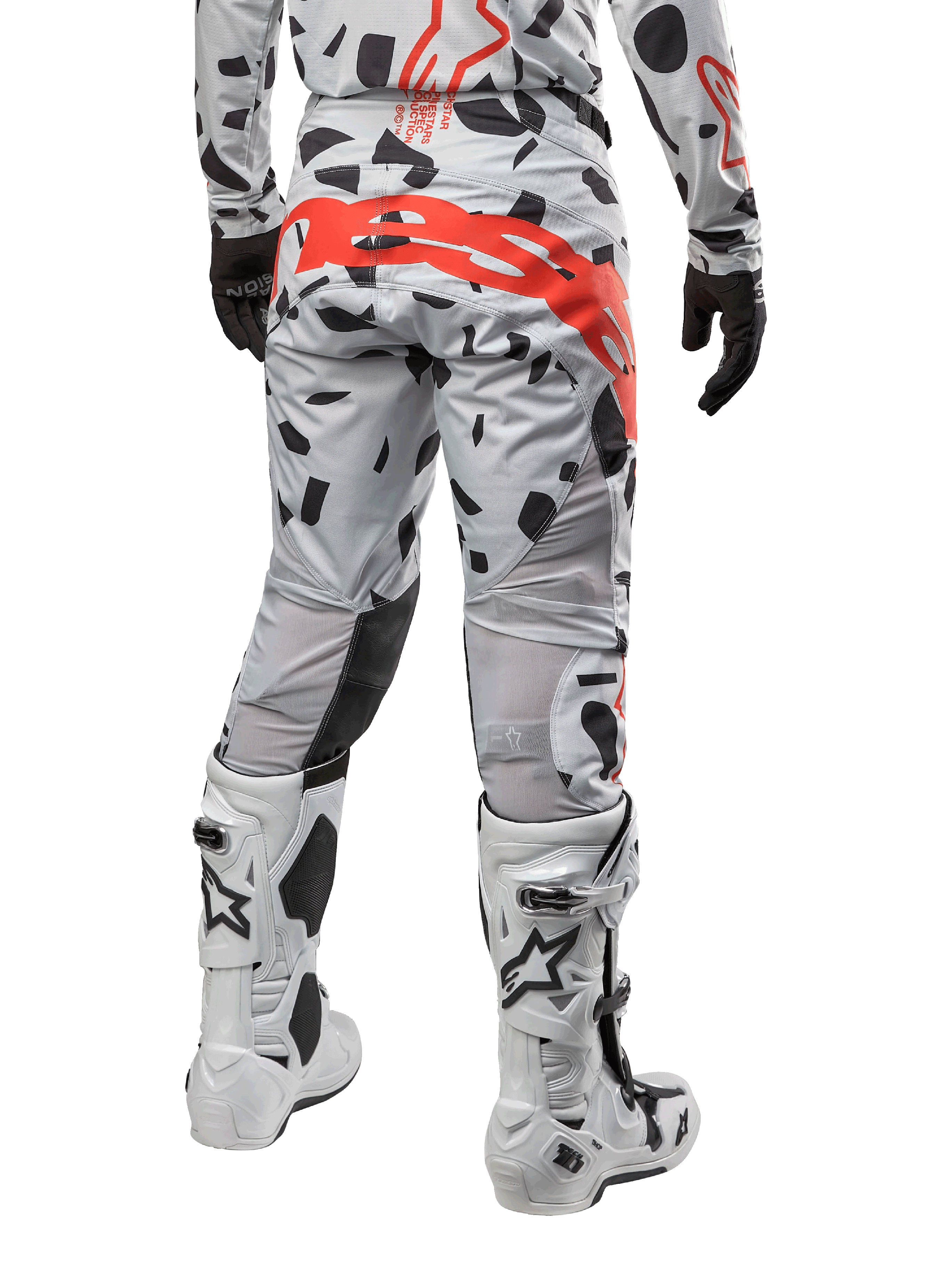 Alpinestars Techstar Rantera Pants 2024, spodnie motocrossowe, kolor Haze Gray Camo, czarne wzory kamuflażu i duże czerwone logo Alpinestars na siedzeniu, widok z tyłu w białych butach i pasującej odzieży wyścigowej
