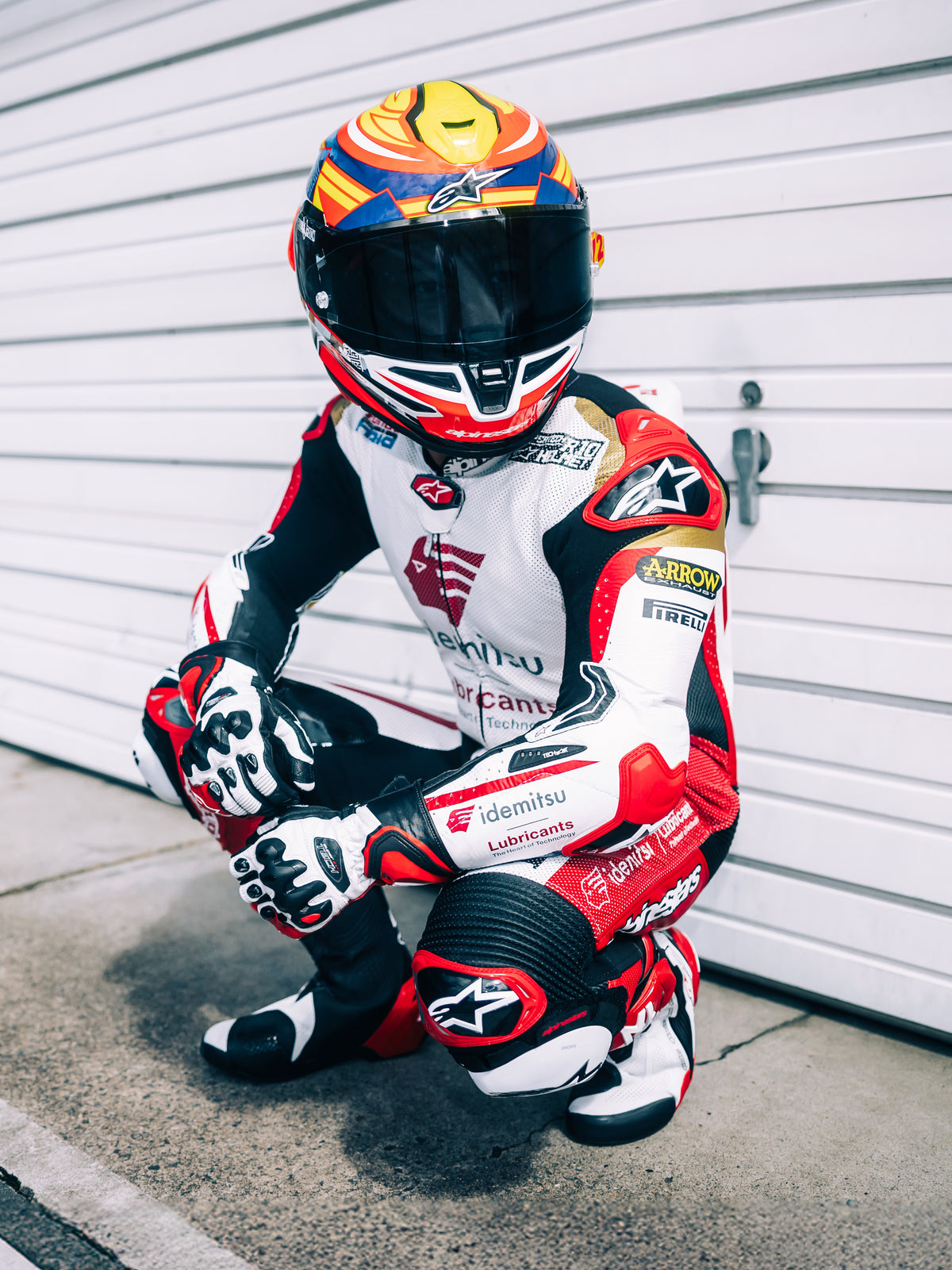 Alpinestars S-R7 Taiyo Furusato Helmet, Full Face Motorcycle Racing Helmet, Red, White, Blue and Yellow Fluo, ECE 22.06 certified, worn by motorcycle racer in full racing leather suit with tinted visor.