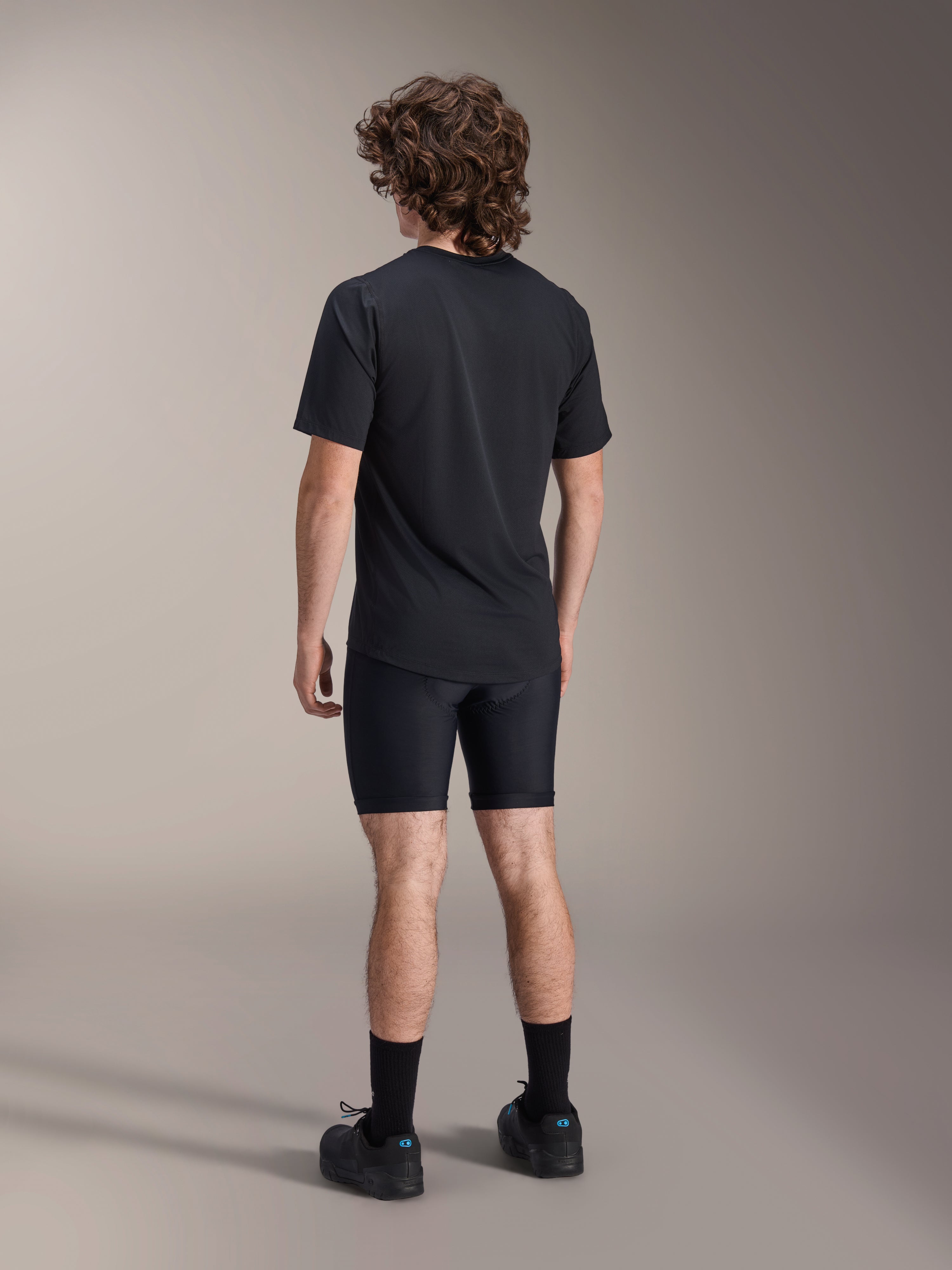 Alpinestars A-Dura Liner Shorts, czarne rowerowe spodenki wewnętrzne, widok z tyłu na modelu, dopasowany elastyczny materiał z widocznymi szwami wkładki chamois, zestawione z czarnym t-shirtem i butami rowerowymi, odzież do kolarstwa górskiego
