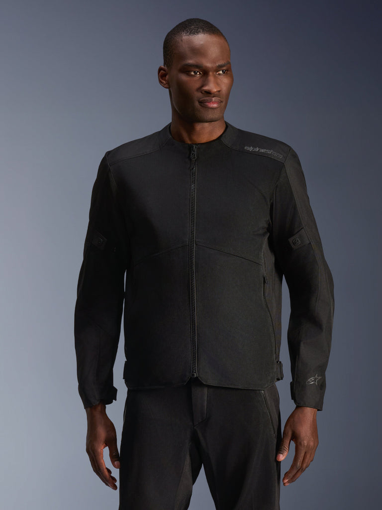 Male model wearing Alpinestars C-1 Air Jacket in Black, contemporary motorcycle jacket with extensive tech mesh panels and a full front zipper, paired with matching black riding pants, urban lifestyle and commuting aesthetic