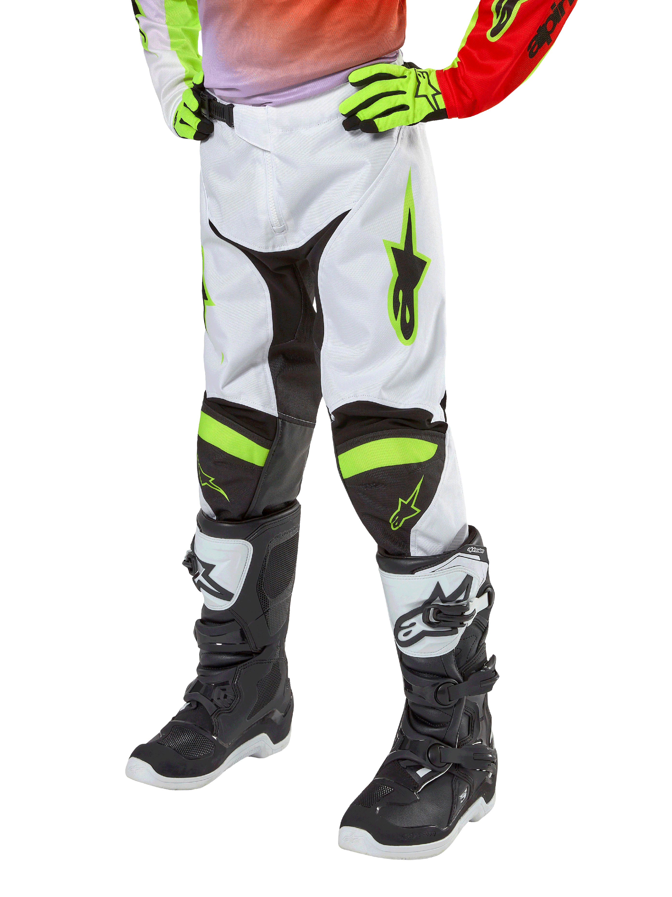 Alpinestars Youth 2024 Racer Lucent Pants, spodnie motocrossowe, białe, neonowo-czerwone i żółte fluo, widok na dolną część ciała z czarnymi elastycznymi panelami i neonowymi akcentami, noszone z czarno-białymi butami wyścigowymi i neonowo-żółtymi rękawicami, techniczna odzież terenowa dla młodzieży