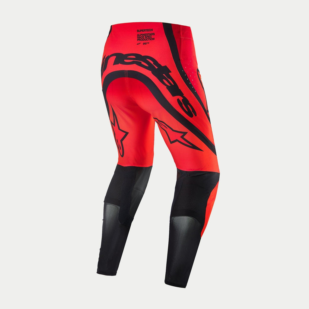 Alpinestars Supertech Ember LE Pants, spodnie motocrossowe, kolor czerwony fluo i jasnoczerwony z czarnymi akcentami, widok z tyłu z wyraźnym czarnym brandingiem Alpinestars na siedzeniu, logo gwiazdy na udach oraz techniczne panele z siatki na dolnej części nogawek